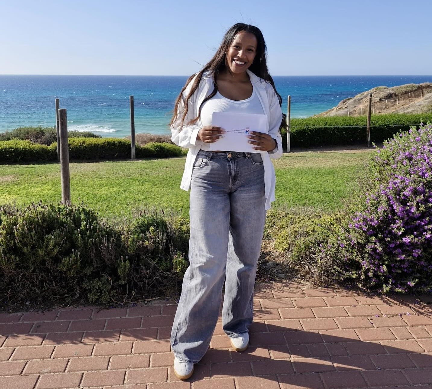 נערה וברקע דשא וים נשקף מרחוק