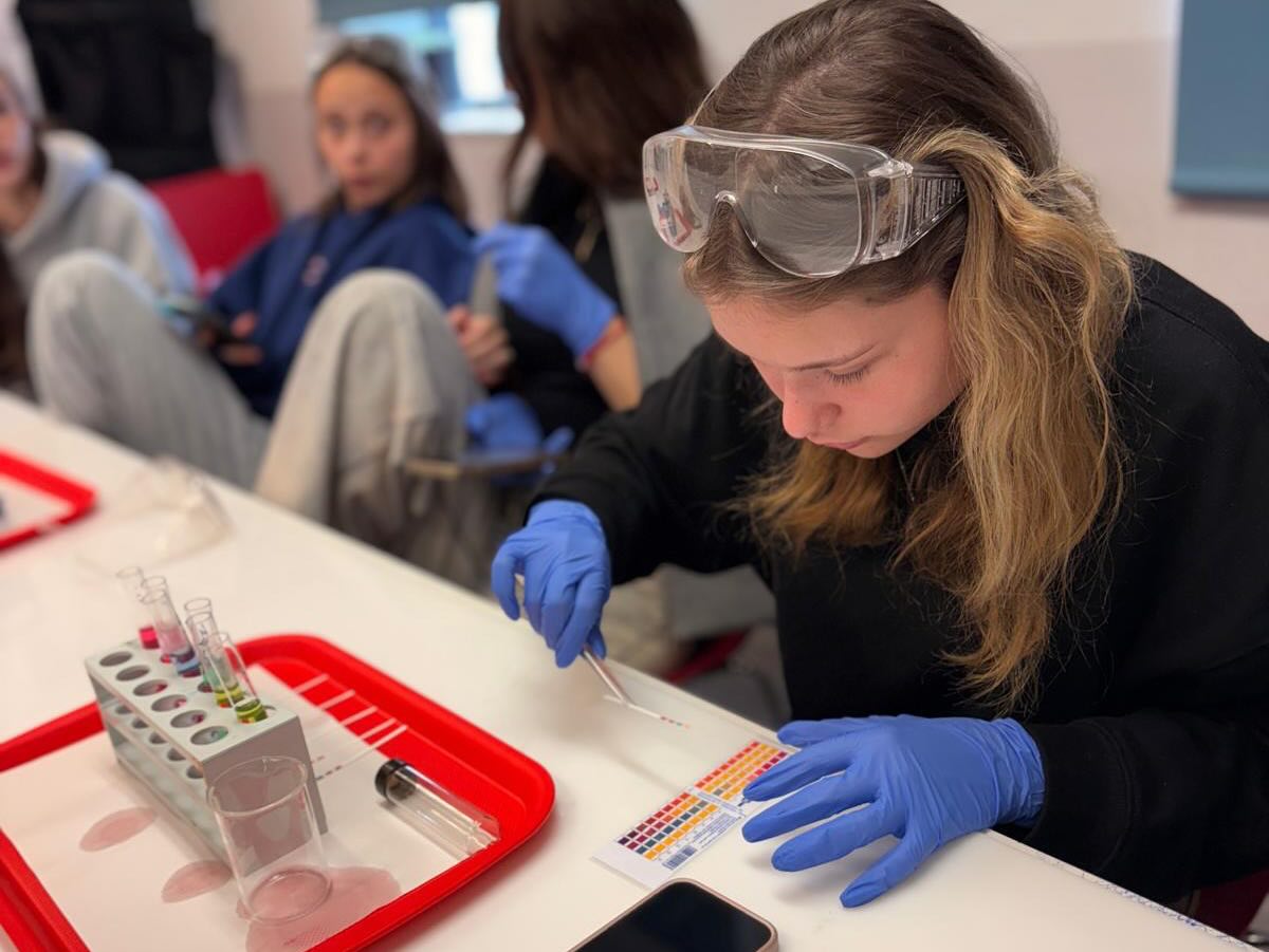 נערה עם משקפי מגן במעבדה וברקע נערות נוספות